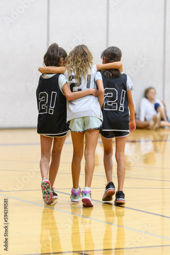 Young child basketball players helping a teammate off of the court after an injury while playing in a game
