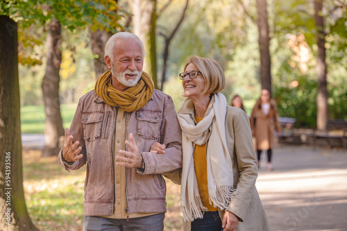 Fotografija Cheerful pensioners enjoying their life walking together in the park and talking