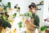 Woman plant breeder examines and admires home plants in a pot from her collection at home on the shelves. Search for pests, care, watering, fertilizers. Home crop production