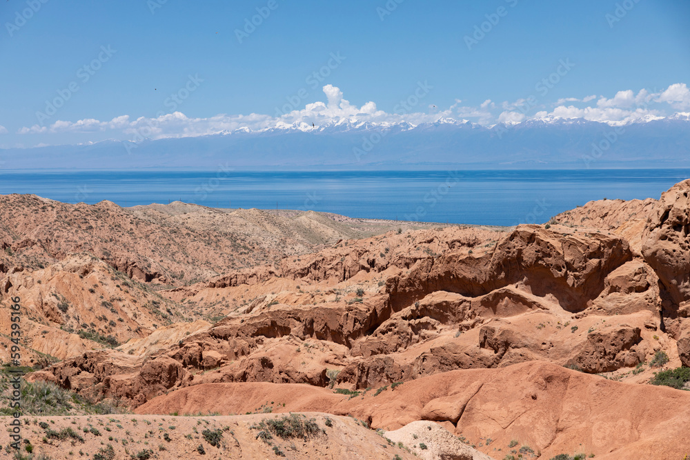 The beautiful wasteland of Skazka Canyon with Lake Issyk-Kul in the background in Kyrgyzstan.