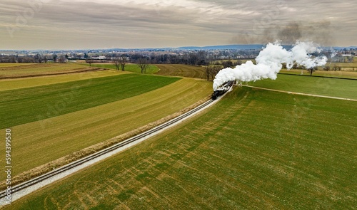 Obraz na plátně Vintage locomotive train chugging along railroad tracks in a scenic countryside