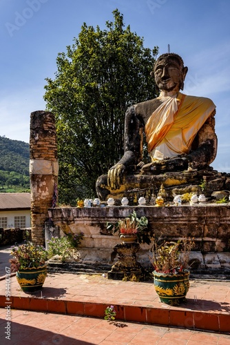 Vertical shot of an ancient and worn statue of Buddha in Wat Phiawat, Xiangkhouang, Laos photo