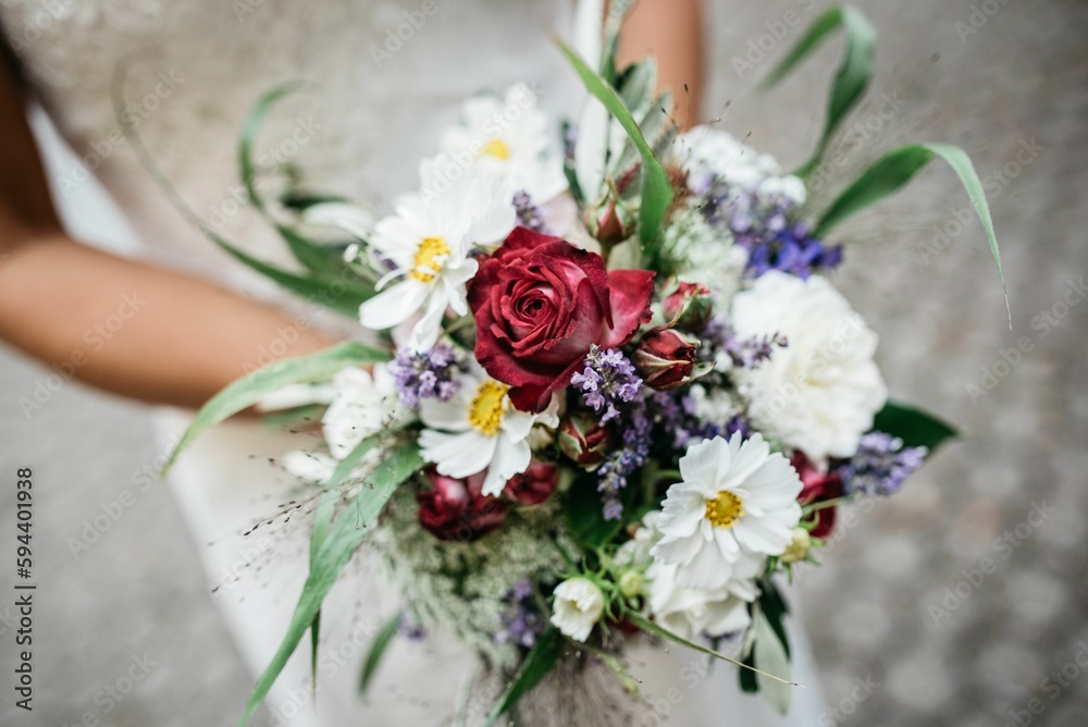 Bouquet of flowers in the hand of a bride in a white dress