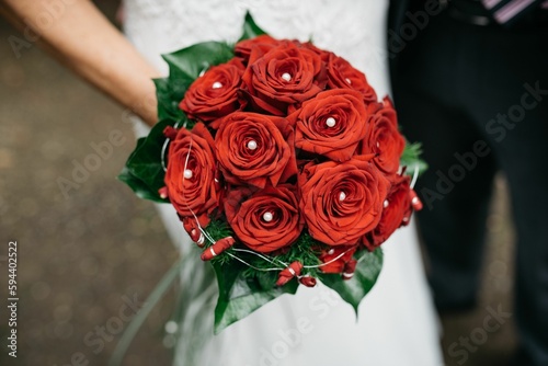 a person holding a wedding bouquet with red roses in it