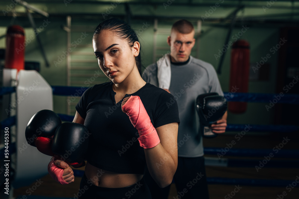 A beautiful determent woman boxer is looking at the camera after a hard training