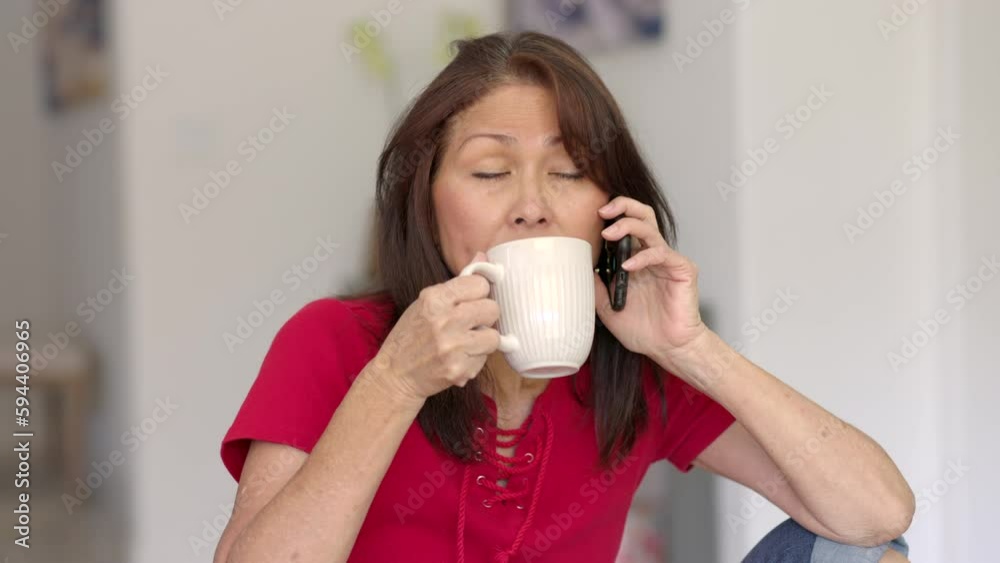 Close up smiling attractive woman talking on mobile cell phone elbow on knee relaxing drinking coffee Close up smiling attractive woman talking on mobile cell phone elbow on knee relaxing drinking coffee