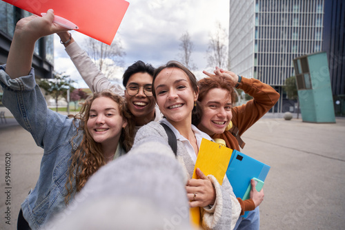 Smiling multiracial college students taking a selfie back to school. Happy friends photo together outside campus university holding folders. Cheerful classmates young people pose and amused. 