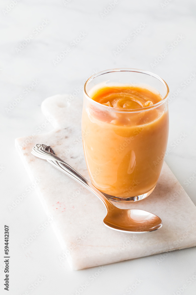 Freshly made creamy salted caramel dessert topping in a small glass.