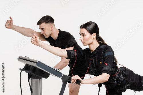 Group workout training in EMS suit, which applies electrical impulses to activate muscles. Trainer shows an example of the exercise using EMS electrical muscle stimulation suit.