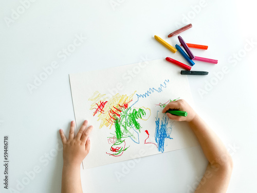 small child draws with pastel crayons on white table. fathers day