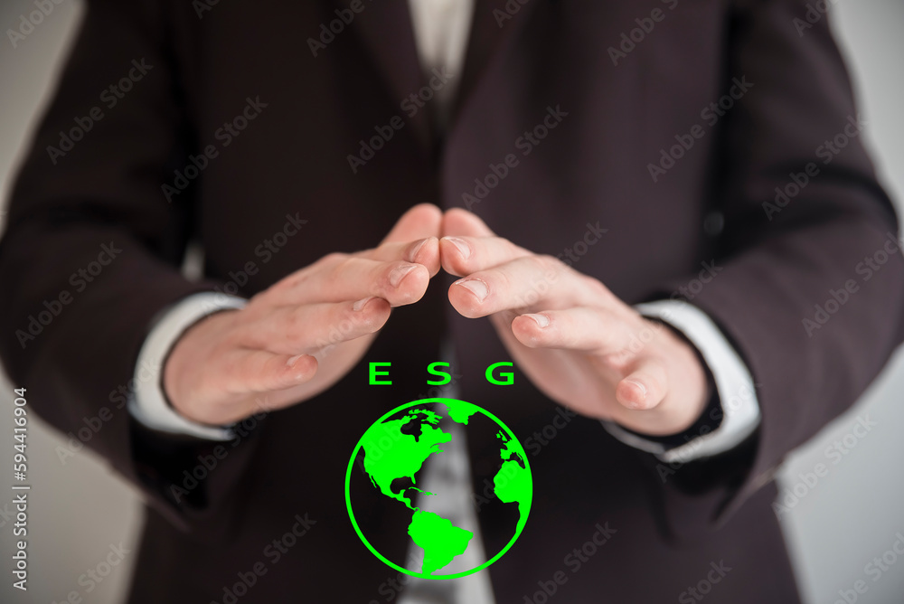 Świadomość biznesowa w zakresie ESG. Dłonie mężczyzny w marynarce przykrywające widok zielonej kuli ziemskiej z napisem ESG. - obrazy, fototapety, plakaty 
