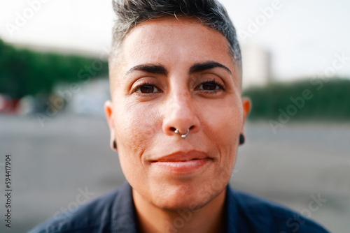 Authentic portrait of gay lesbian woman smiling on camera outdoor - Lgbt nonbinary people concept - Main focus on eyes