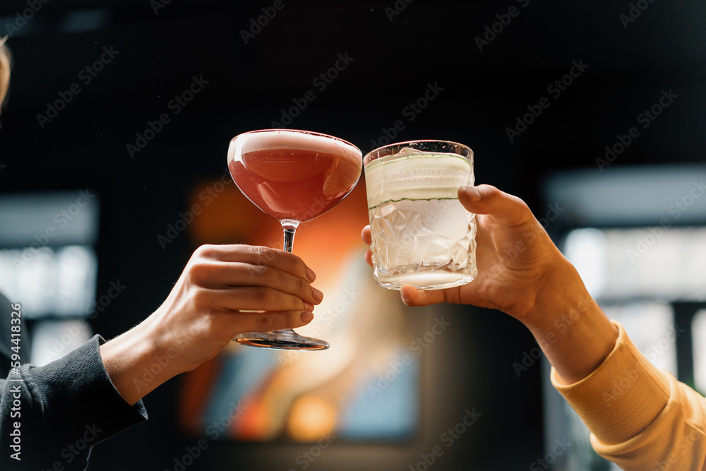 Close up of two people cheering cocktails in a bar or disco club drinks and cocktails concept - obrazy, fototapety, plakaty 