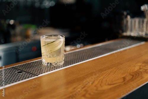 freshly prepared gin garden alcoholic cocktail with a cucumber slicer stands on the bar counter in the bar club