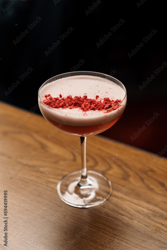 delicious pink freshly prepared milk punch cocktail with raspberries stands on the bar counter