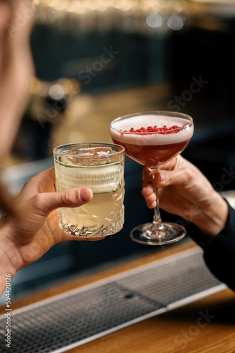 Close up of two people cheering cocktails in a bar or disco club drinks and cocktails concept