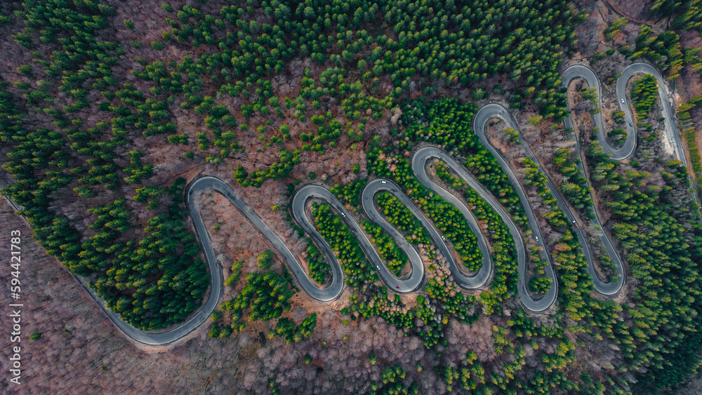 Aerial photography of a winding road in the mountains with serpentines and curves. Photography was shot from a drone at a higher altitude. Aerial photography of a winding road in the mountains with serpentines and curves. Photography was shot from a drone at a higher altitude.