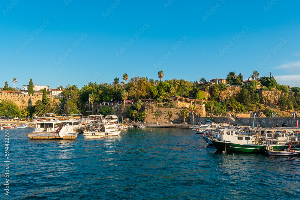 View of a cozy little historical port with turquoise water and boats in the city of Antalya.