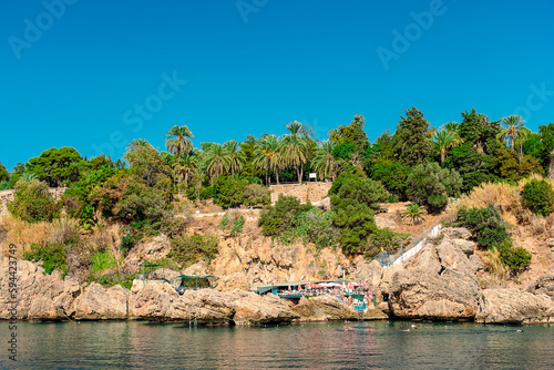 View from the sea to a rocky shore with high-rise buildings in the city of Antalya.