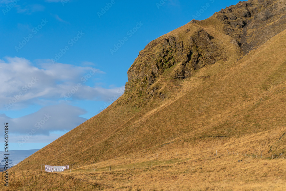 White laundry on the line with golden mountain. Reynisfjall tuff mountain on the South Coast of Iceland near Vik. 