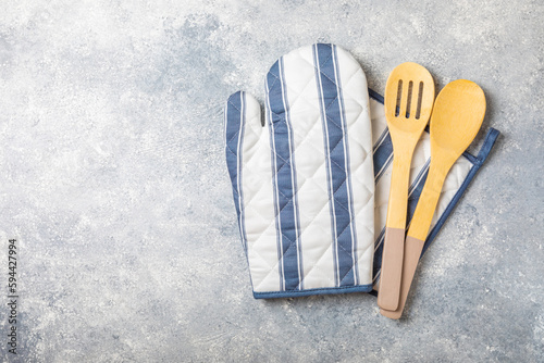 Wooden kitchen utensils, potholder and glove on the table, top view. Kitchen Mitten, oven mitt and wooden cutlery on a gray marble table. Kitchen accessories.Kitchen concept. photo