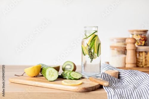 Infused water with cucumber, lemon and thyme in glass bottle on wooden table. Diet, detox, healthy eating, weight loss concept