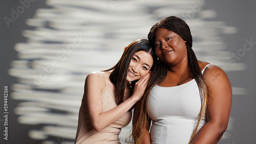 Young cheerful women embracing imperfections, creating skincare campaign on camera, advertising empowering message and self love. Diverse girls promoting femininity and beauty products.
