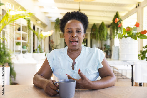Portrait of happy senior african american woman with cup of coffee having video call