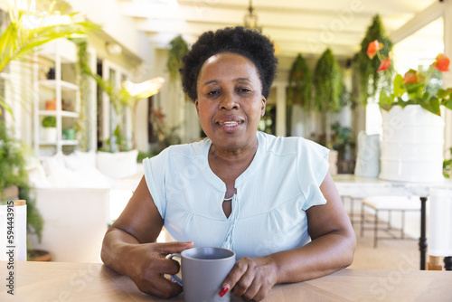 Portrait of happy senior african american woman with cup of coffee having video call