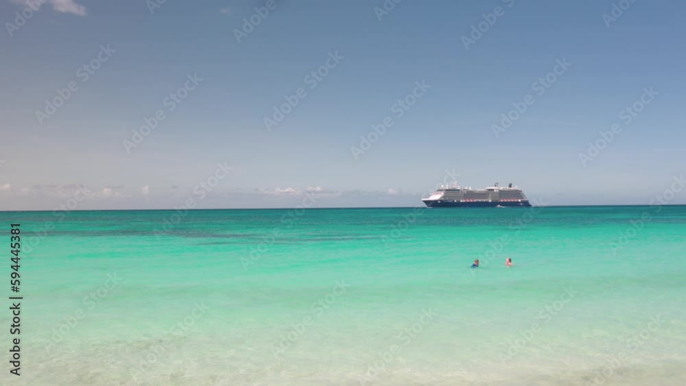 Couple of tourists swimming in ocean and cruise ship passing by on background. Aruba. Couple of tourists swimming in ocean and cruise ship passing by on background. Aruba.