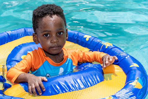Young boy with an inflatable floaty in an outdoor swimming pool