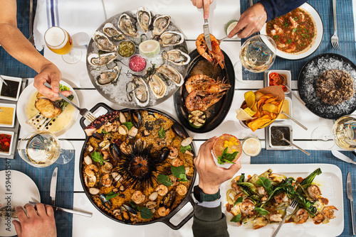 Fotografie plano cenital de varios platos de mariscos y copas de vino sobre manteles azules