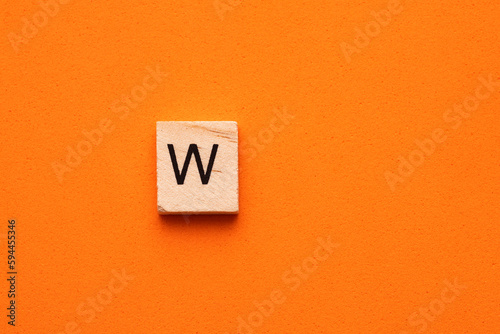 Alphabet capital letter W on wooden square tile - Orange foamy background