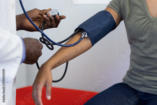 Photos Midsection of frican american male doctor measuring blood pressure of biracial f