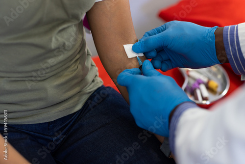 African american male doctor and biracial female patient collectiong blood at doctor s office