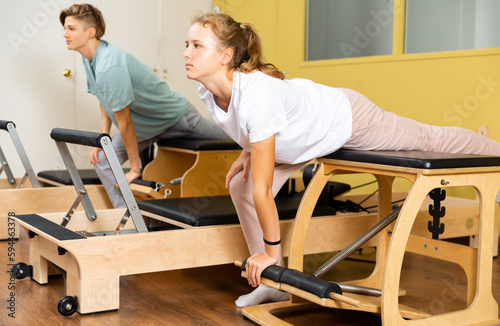 Young boy and girl performing set of pilates exercises on reformer in modern fitness studio