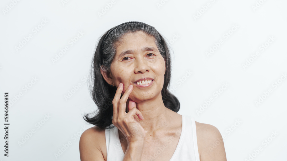 Close up face of female elderly mature older asian chinese housewife applies anti aging facial cream on face, old skincare treatment Close up face of female elderly mature older asian chinese housewife applies anti aging facial cream on face, old skincare treatment
