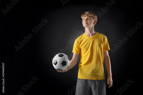 Teenage boy with soccer ball on black background. Space for text