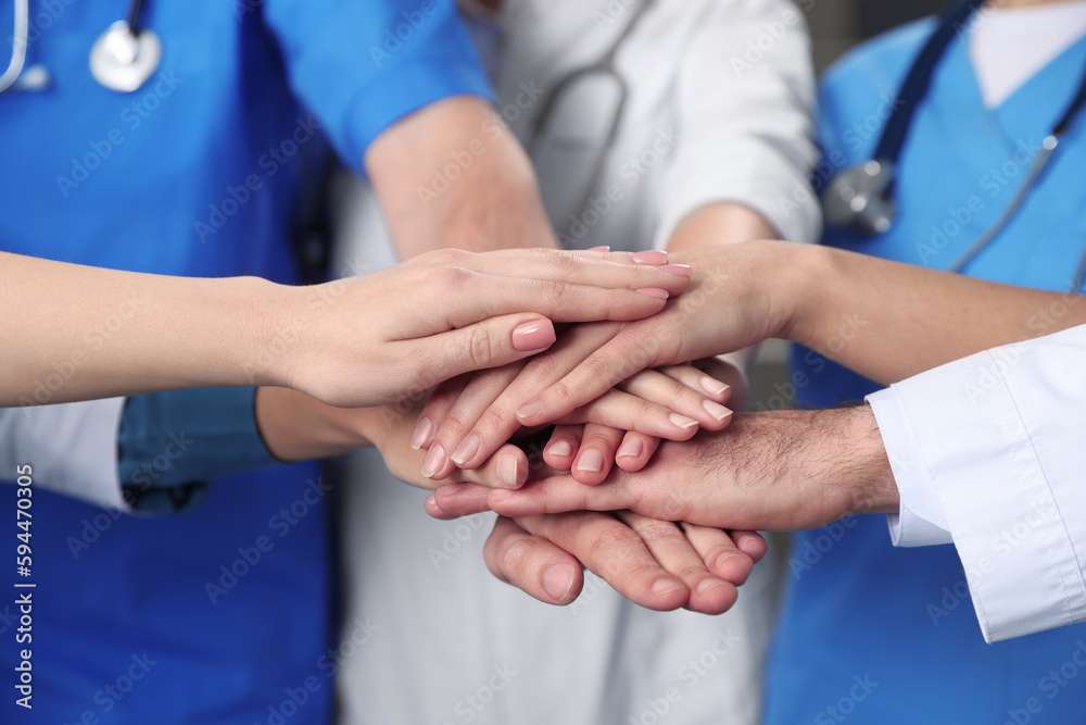 Team of medical doctors putting hands together indoors, closeup Team of medical doctors putting hands together indoors, closeup