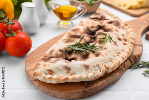 Tasty pizza calzone with rosemary and different products on white table, closeup