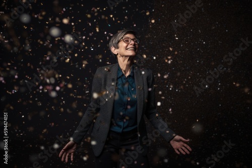 elderly woman in black suit and glasses on black background with falling snow