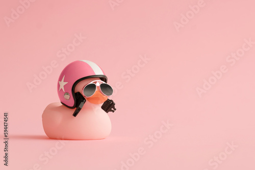 Creative composition made of pink cute little rubber duckling with a helmet and sunglasses on pink background.Summer minimal duck concept. Creative art, Contemporary style.Writing space, copy space.