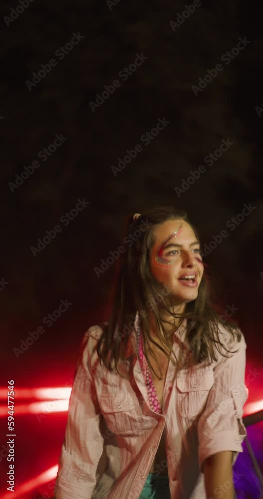 Vertical video portrait of a girl with makeup and glitters on her face dancing in front of stage with flashing lights. Vertical video portrait of a girl with makeup and glitters on her face dancing in front of stage with flashing lights.