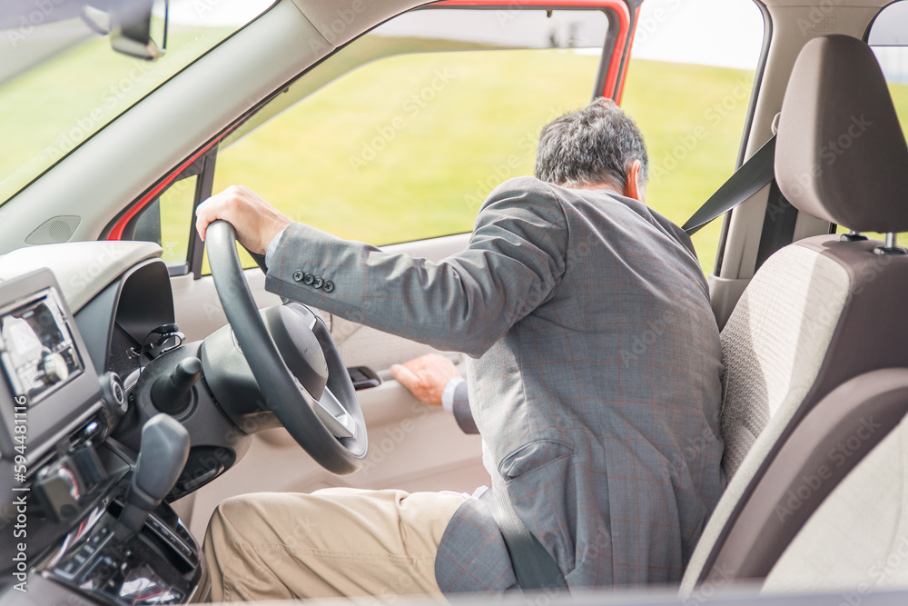 駐車場で自動車のドアを開けてバックする高齢者ドライバーの男性
駐車場で自動車のドアを開けてバックする高齢者ドライバーの男性