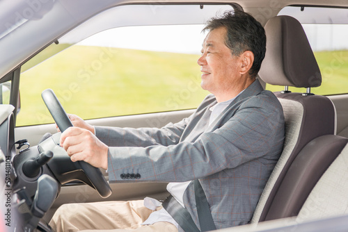 自動車の運転をする笑顔の高齢者ドライバーの男性  © buritora
