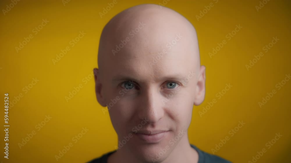 Male with blue eyes and bright skin lifting his head and looking straight towards the camera with a smile on a yellow background, Slow motion. Male with blue eyes and bright skin lifting his head and looking straight towards the camera with a smile on a yellow background, Slow motion.