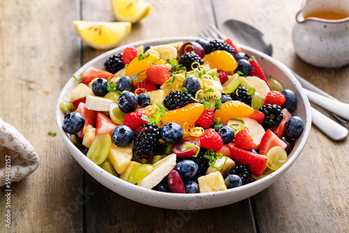 Fruit salad on a wooden table with berries and honey dressing