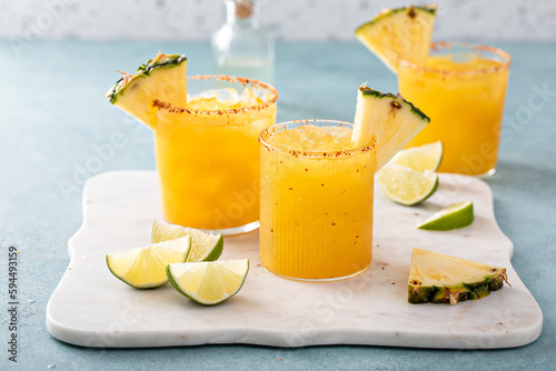 Pineapple margarita cocktail in glasses with tajin rim photo