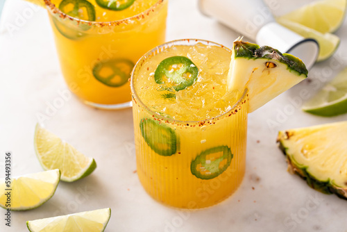 Pineapple jalapeno margarita cocktail in glasses with tajin rim photo