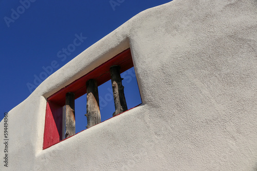 A white stucco wall and cedar window  with blue sky located in the 300-Year-old Historic Old Town Albuquerque New Mexico photo